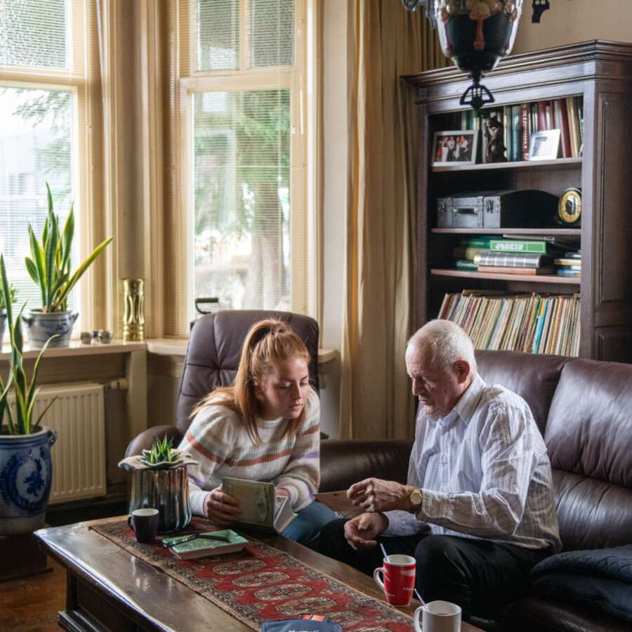 Nederland - Illustratief beeld. Oudere heer en jonge vrouw kijken samen naar oude foto's. foto: ANP / Hollandse Hoogte / Patricia Rehe